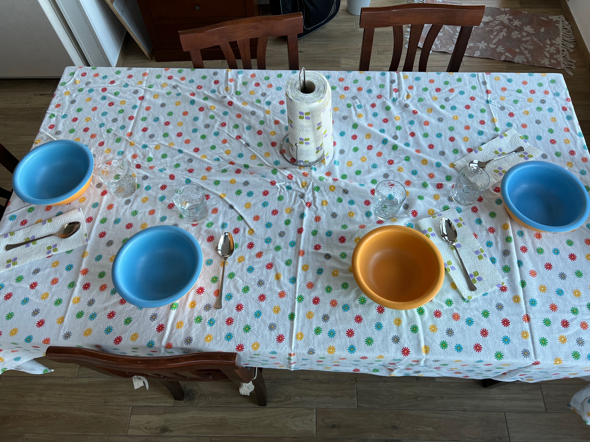 Nell'immagine una tavola apparecchiata per 4 persone, con ciotole da zuppa,, su una tovaglia fiorata.