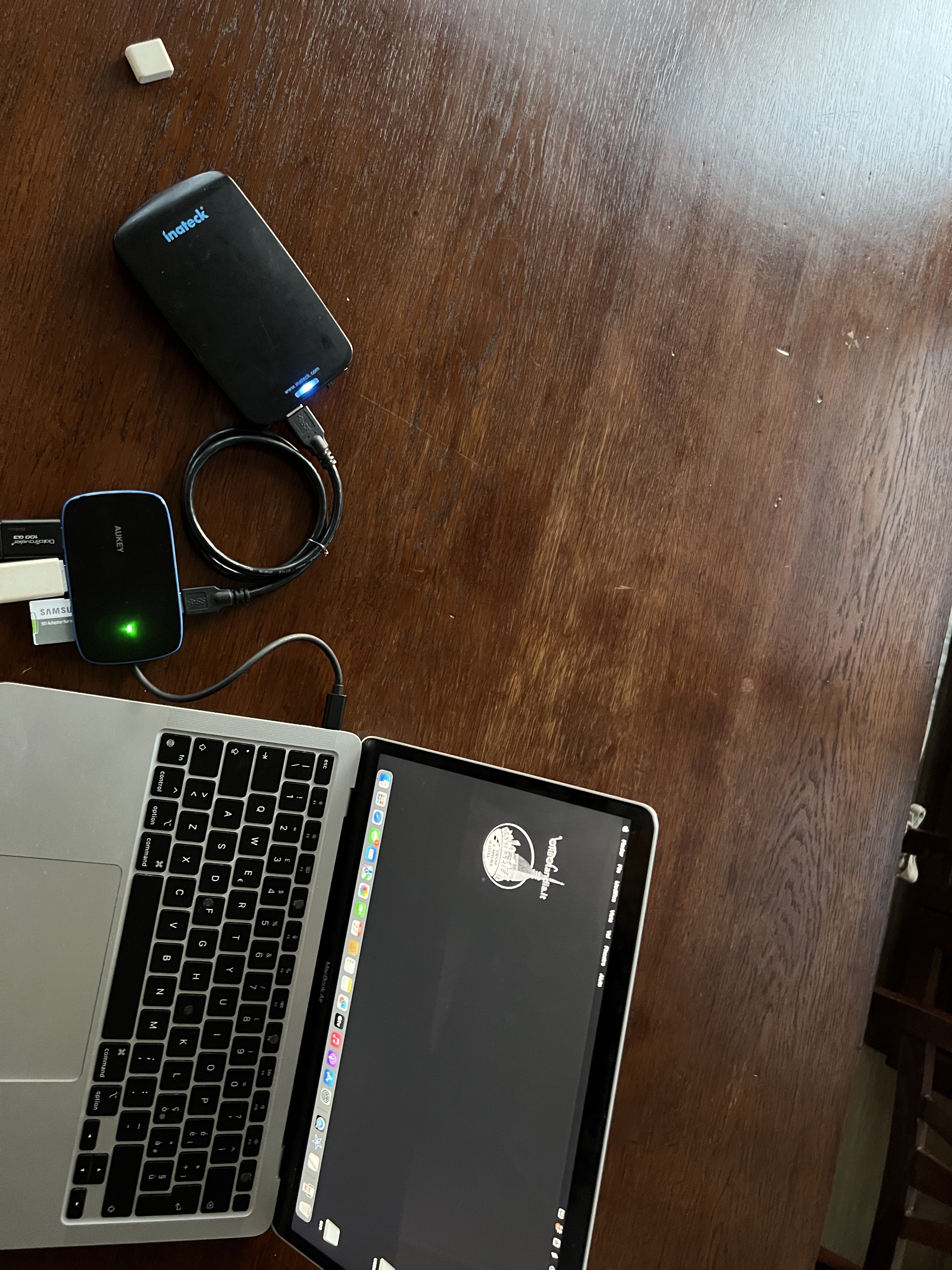 Nell'immagine un MacBook Air al quale è collegato un dispositivo Dock multiporta, al quale sono collegati diversi dispositivi di archiviazione: due chiavette USB, un hard disk e una scheda SD.